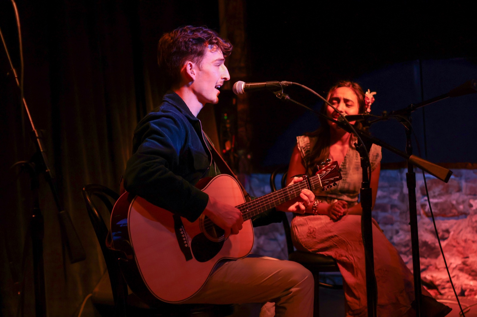 Ben Hulbert singing and playing acoustic guitar during an intimate seated performance