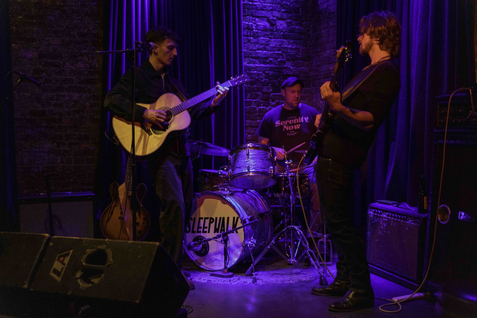 Ben Hulbert performing guitar onstage with bass and drums